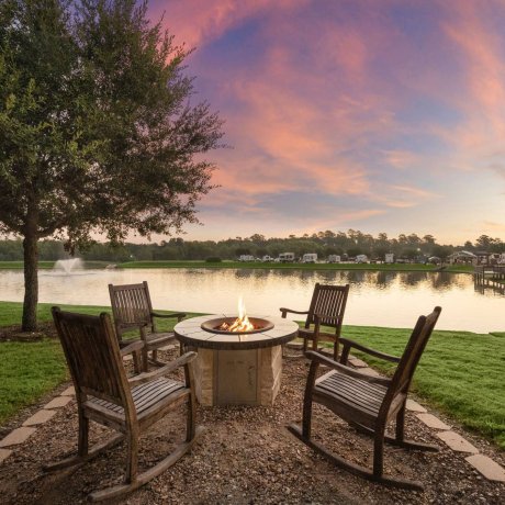 Lakeside fire pit with wooden rocking chairs at sunset at Westlake RV Resort in Houston TX