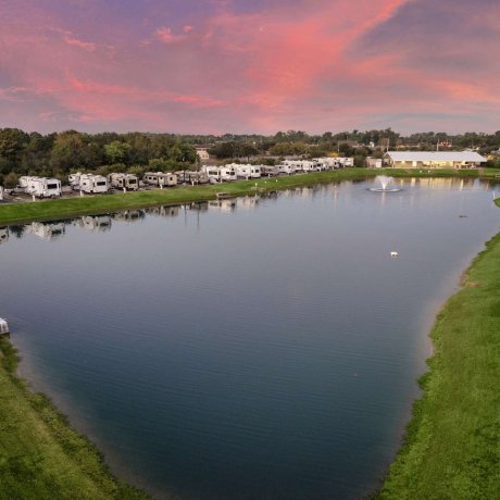 Scenic lake surrounded by RV sites with fountain feature at Fallbrook RV Resort in Houston, TX.