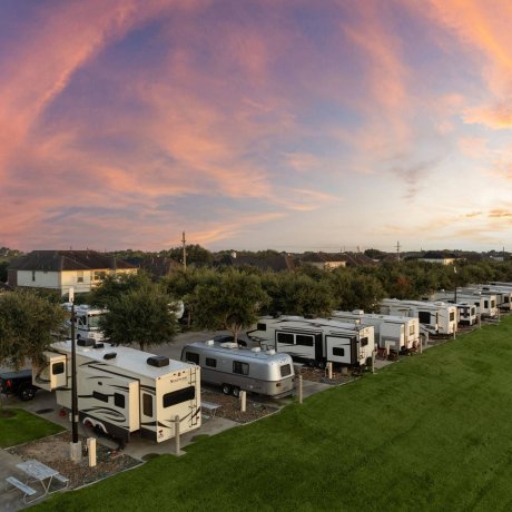 Twilight view of RVs along grassy area at Westlake RV Resort in Houston, TX