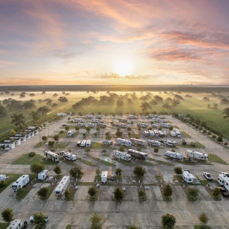 Twilight view of RV sites at Brazoria Lakes RV Resort with morning mist, pasture, and trees during sunrise in Brazoria, TX