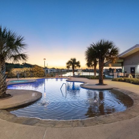 Highway 6 RV Resort pool shallow-entry w/ palm trees, lounge chairs and spa at dusk — Houston, TX pet-friendly monthly RV stays