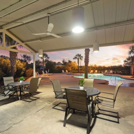 Covered outdoor seating area overlooking the resort-style pool at sunset at Fallbrook RV Resort in Houston, Texas.