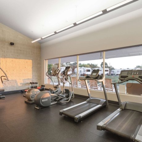 Modern fitness center at Fallbrook RV Resort with treadmills, ellipticals, and strength equipment.