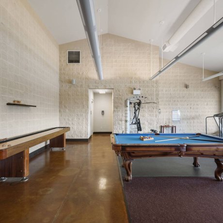 Game room and fitness center with pool table, shuffleboard, and gym equipment at Westlake RV Resort in Houston, TX