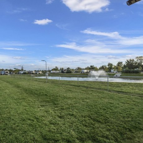 Large, fenced, grassy dog park and pet area with pet waste station overlooking the fishing lake at Lakeview RV Resort