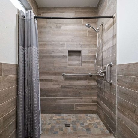 Spacious tiled shower with grab bars at Allstar RV Resort in Houston, TX