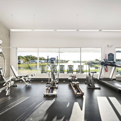 Fitness center at Highway 6 RV Resort with cardio machines, free weights, and panoramic lake views — Houston, TX pet-friendly monthly stays