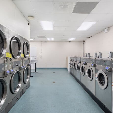 Laundry room with professional-grade washers and dryers inside the clubhouse at Brazoria Lakes RV Resort in Brazoria, TX