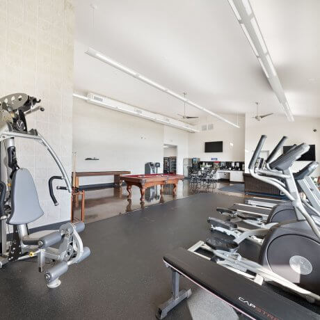 Clubhouse workout area at Brazoria Lakes RV Resort with pool table, shuffleboard, fridge, coffee maker, and popcorn machine in Brazoria, TX