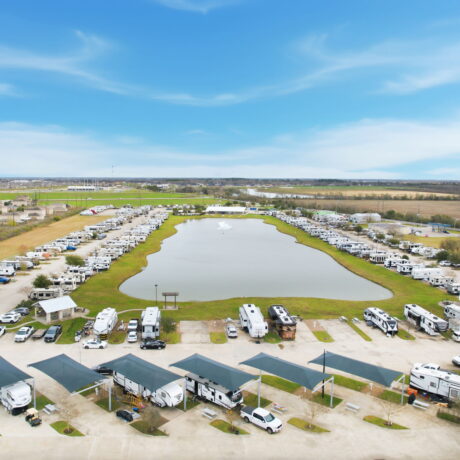 Aerial view of Mont Belvieu RV Resort near Houston Texas showing full hookup RV sites surrounding a private lake with covered canopy sites