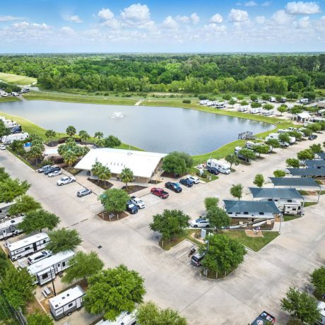 Aerial view of shaded RV sites and lake with fountain at Westlake RV Resort in Houston, TX 77084
