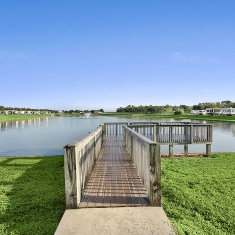 Wooden dock overlooking private lake with RV sites and fountain at Westlake RV Resort in Houston TX