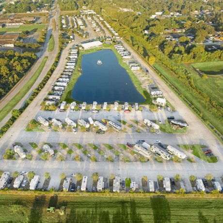 Aerial view of Fallbrook RV Resort in North Houston showcasing full RV pad layout, central lake with fountain, and tree-lined surroundings.
