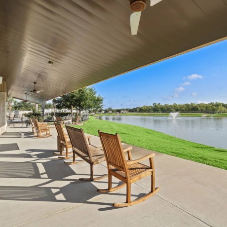 Covered patio with wooden rocking chairs overlooking lake and fountain at Westlake RV Resort Houston