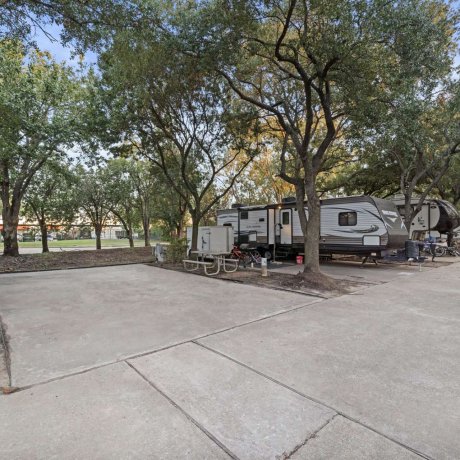 Spacious RV pad with picnic table and full hookups under mature shade trees at Allstar RV Resort in Houston, TX