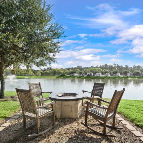 Lakefront fire pit area with wooden rocking chairs and fountain view at Westlake RV Resort in Houston