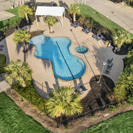 Aerial pool view at Highway 6 RV Resort with palm trees, shaded pavilion, spa and fenced deck — Houston, TX pet-friendly monthly stays