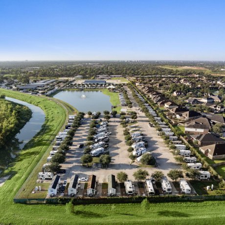 Wide aerial view of Westlake RV Resort with RV sites, park model rentals, and adjacent residential neighborhood in Houston, Texas