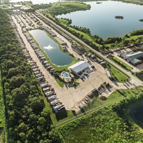 Aerial view of Highway 6 RV Resort showing lakeside full-hookup RV sites, clubhouse, pool and fountain — ideal for Winter Texans and monthly stays.