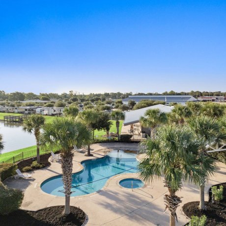Resort-style pool and hot tub with palm trees and lake view at Westlake RV Resort in Houston, TX