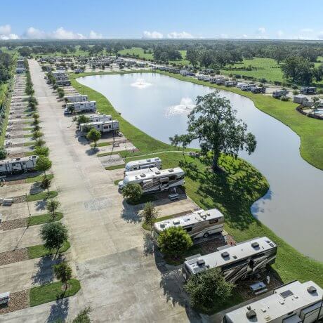 Aerial view of Brazoria Lakes RV Resort with lake, RV pads, fountains, and clubhouse with pool