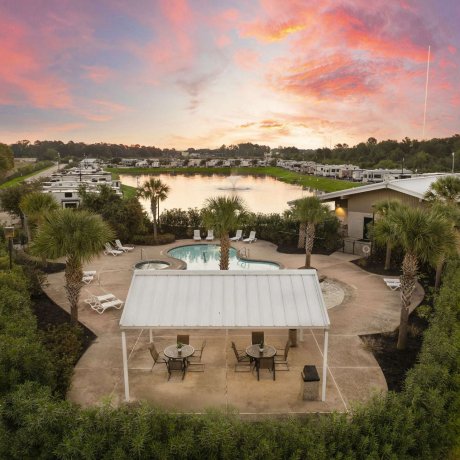 Aerial view of the pool, hot tub, and lakefront RV sites at Fallbrook RV Resort in Houston, TX during sunset.
