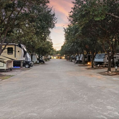 Tree-lined RV sites at twilight with full hookups at Allstar RV Resort in Houston, TX