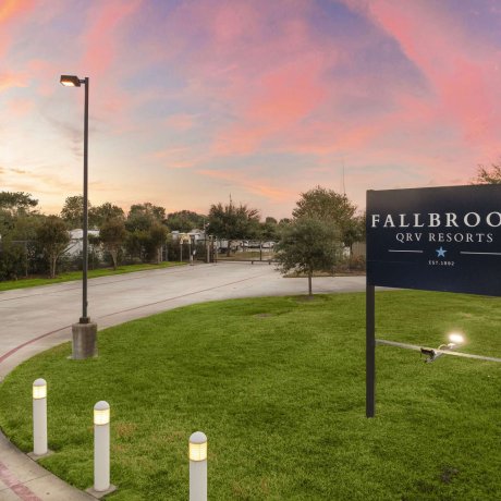 Entrance sign of Fallbrook RV Resort in Houston, TX at twilight, welcoming guests to the gated RV park.
