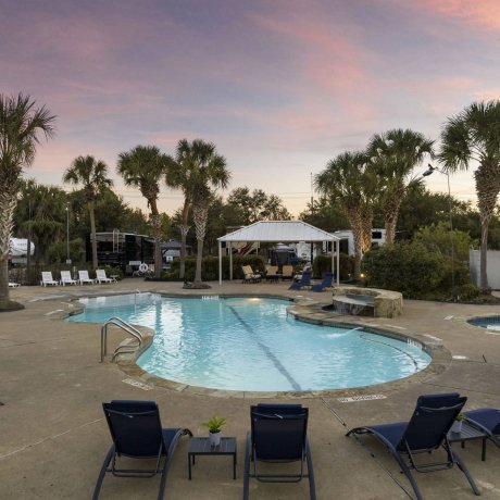 Lakeview RV Resort resort pool at dusk with rock waterfall, hot tub and lounge chairs — Lakeview RV Resort, Houston TX