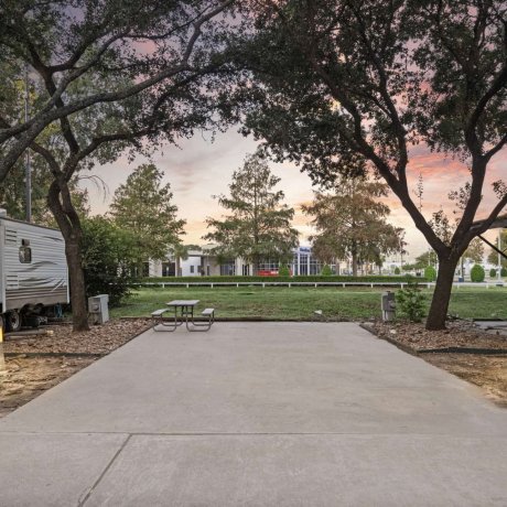 Concrete RV pad site with picnic table and green lawn view at Allstar RV Resort in Houston, TX