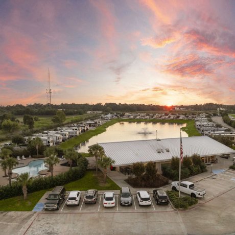 Aerial sunset view of Fallbrook RV Resort in Houston, TX featuring lakefront RV sites, a swimming pool, and main office.