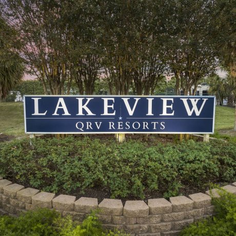 Lakeview QRV Resorts entry sign with landscaped planter and trees at dusk, Houston.