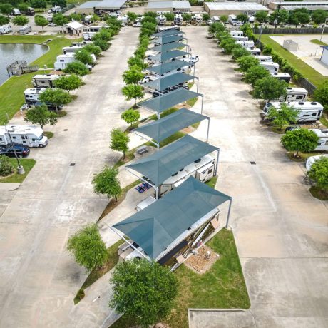 Aerial view of RV site rows at Westlake RV Resort in Houston, TX with shaded pull-thru sites, lakefront RVs, and surrounding trees