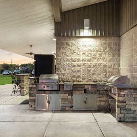 Highway 6 RV Resort outdoor kitchen with built-in stone grills and covered pavilion at twilight — Houston, TX pet-friendly monthly RV stays