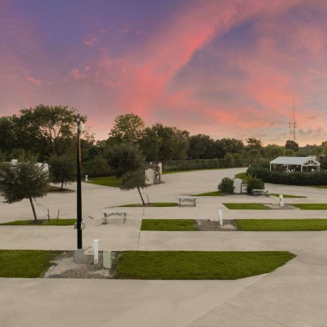 Spacious concrete Pull Through RV pads with full hookups at Fallbrook RV Resort in Northwest Houston during twilight.