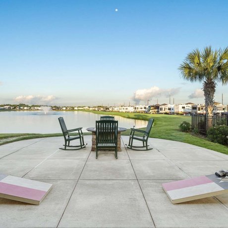 Pondside firepit, rockers and cornhole at Mont Belvieu RV Resort — monthly sites near Baytown refineries