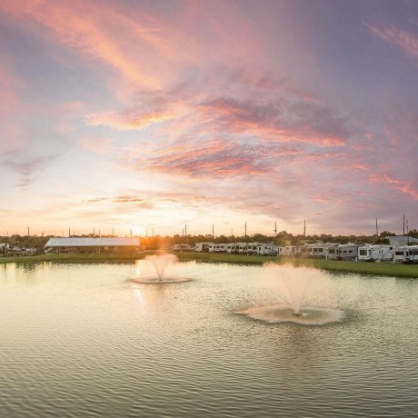 Sunset over pond with twin fountains at Mont Belvieu RV Resort — waterfront RV sites in Baytown, TX