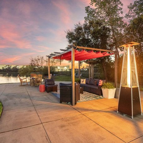 Outdoor seating area with canopy, patio heater, and lake view at Southlake RV Resort in Houston, TX during sunset