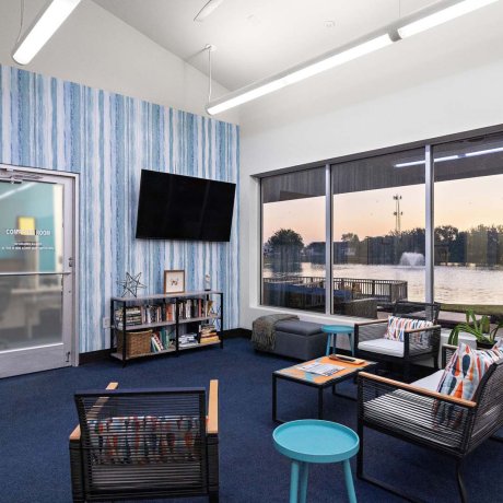 Clubhouse lounge with bookshelves, TV, lake view, and access to computer room at Southlake RV Resort in Houston, TX