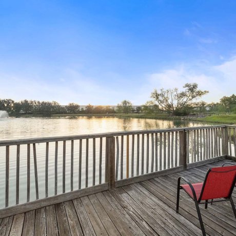 Wooden lakeside dock with red chairs and water fountain at Southlake RV Resort in Houston, TX