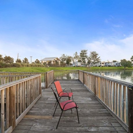 Wooden fishing dock with red chairs and American flag view at Southlake RV Resort in Houston, TX