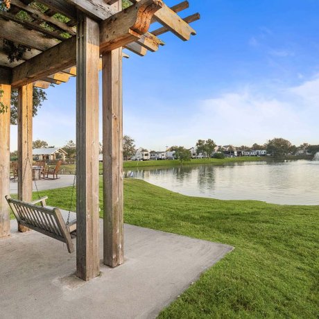 Wooden swing under pergola with lake and fountain view at Southlake RV Resort in Houston, TX