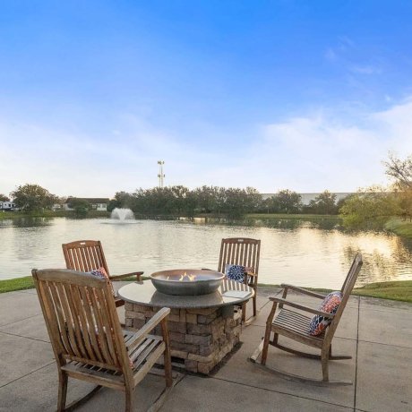 Outdoor fire pit with wooden chairs overlooking the lake at sunset at Southlake RV Resort in Houston, TX