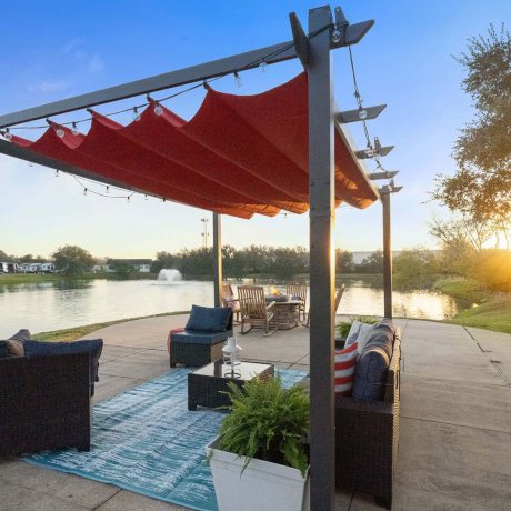 Outdoor lounge with red canopy and lake view at sunset at Southlake RV Resort in Houston, TX