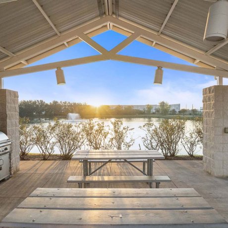 Covered picnic area with BBQ grill and lake view at sunset at Southlake RV Resort in Houston, TX